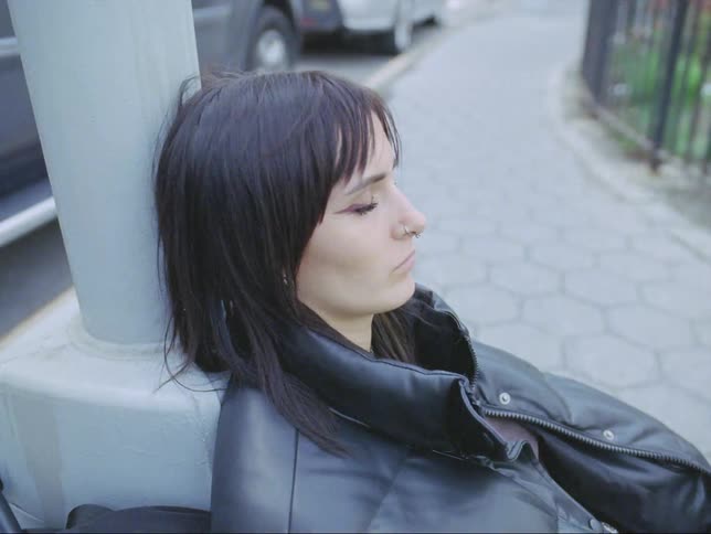 A woman is resting against the lamp post
