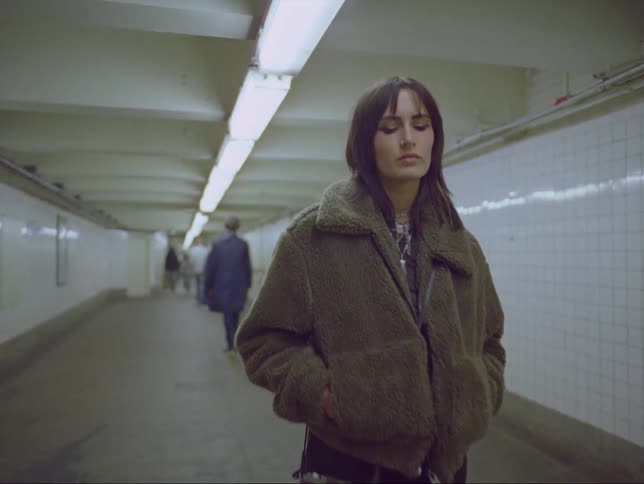 Pedestrians walk past a woman in the subway tunnel