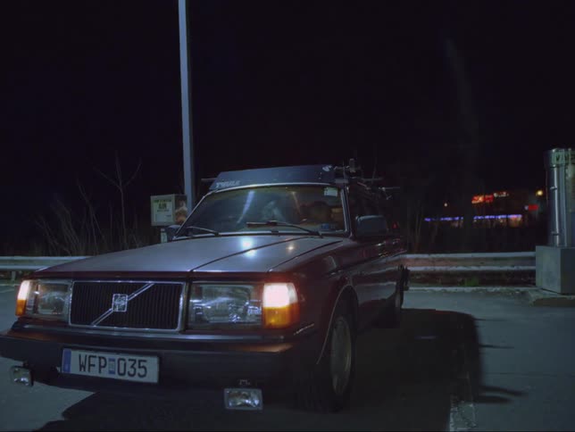 A car is sitting in a remote parking lot with the parking lights on