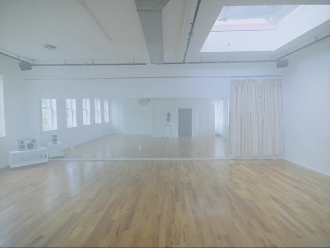 Wall sized mirror reflects empty dance studio with a sky window