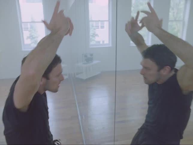 A man dances in front of the mirror