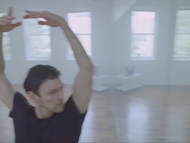 A man is dancing alone in the studio in front of a mirror