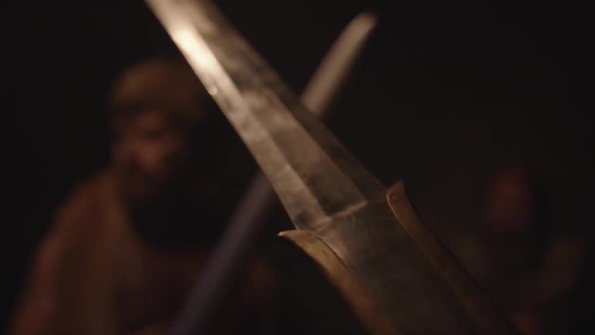 Men holding swords in flickering firelight