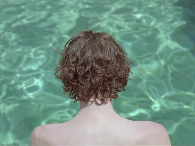 A man dangles his feet in a pool