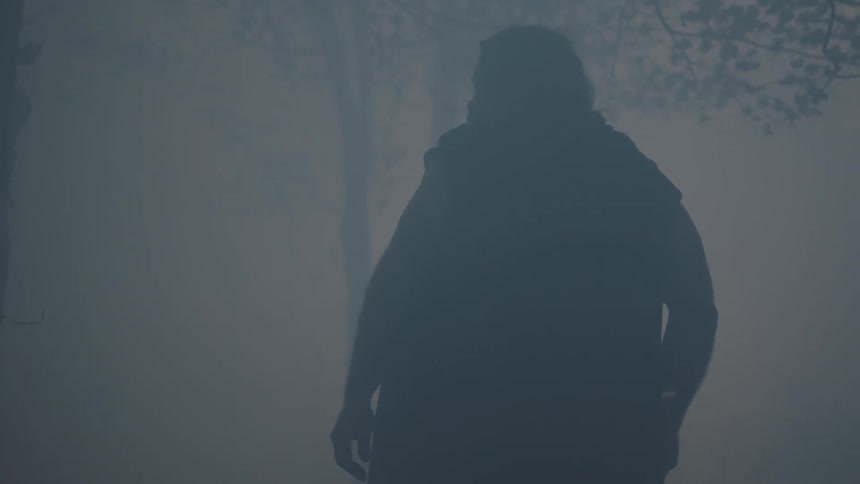 A man is standing in a smoke filled area before walking