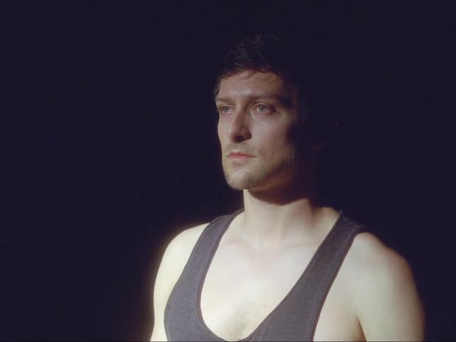 Man standing with eyes closed in dark room opens eyes and walks away