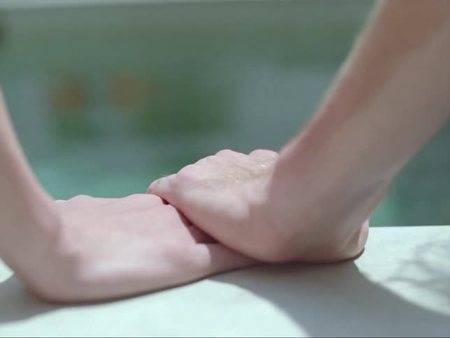 Close up of a mans hand as he moves it and rests it on a womans hand