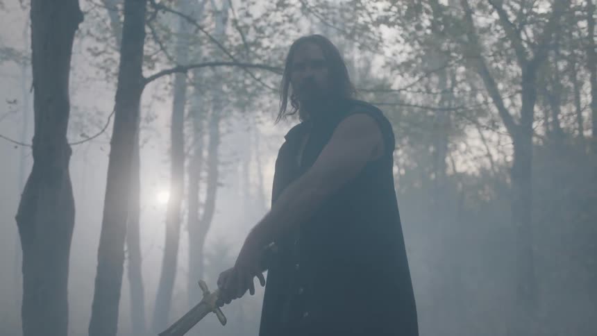 A man carrying a large sword winds up to swing