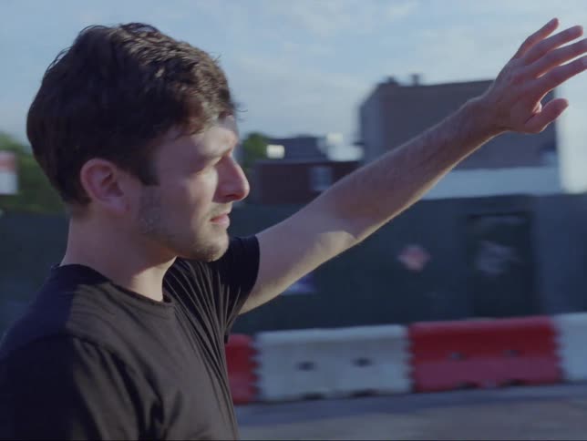 A man is standing outdoors in a downtown city at dusk