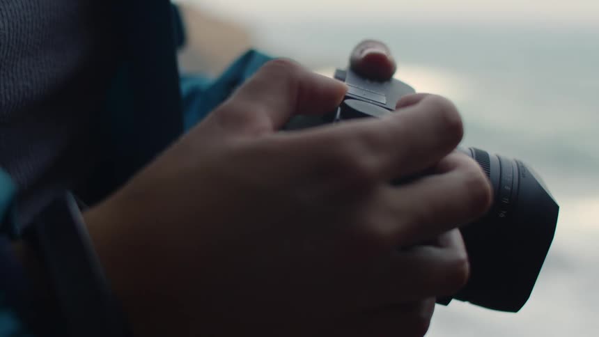 Close up of a person holding a camera and pushing buttons on it