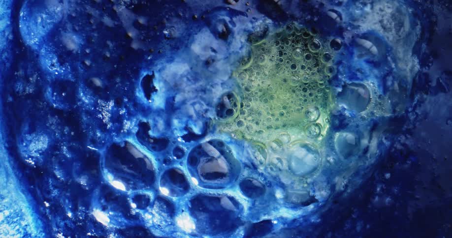 An organic blue and green mass oozes and bubbles rise and pop as it boils from within