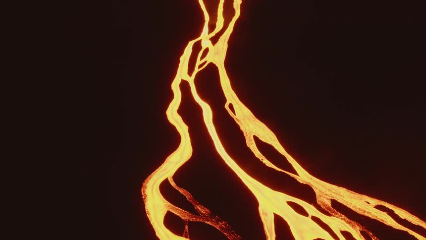 Streams of glowing flowing lava on a black dark slope