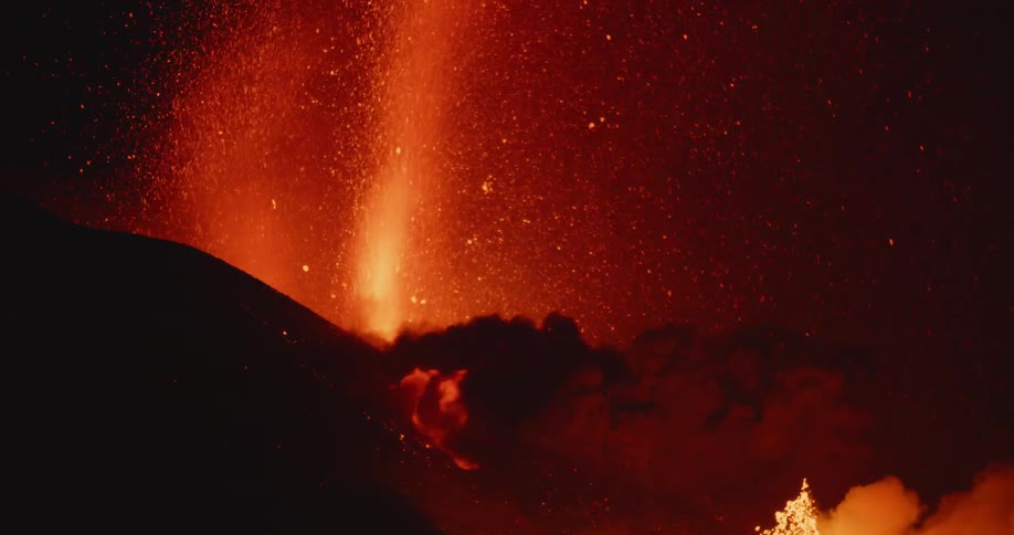 Lava and smoke spew from an erupting volcano at night