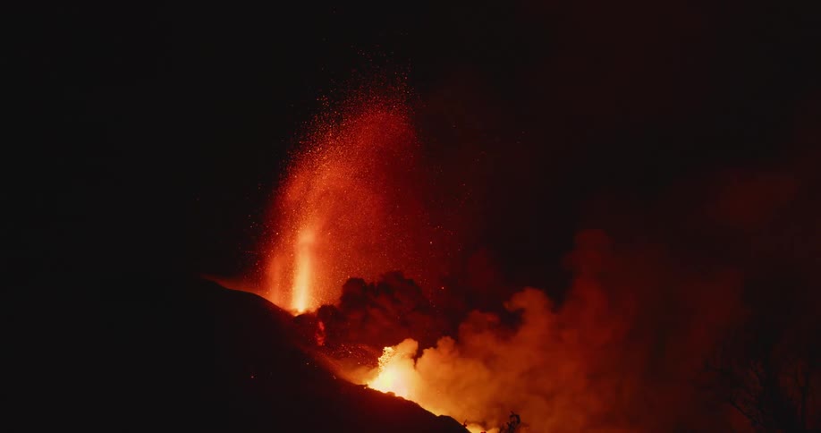 The slope of volcano illuminated by spewing lava at night