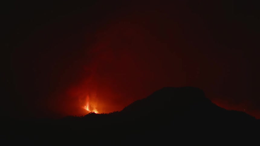 Lava is spewing up from a volcano at night