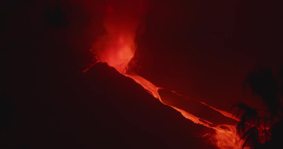 Red hot lava glows as it sprays out of an erupting volcano and flows down the sides