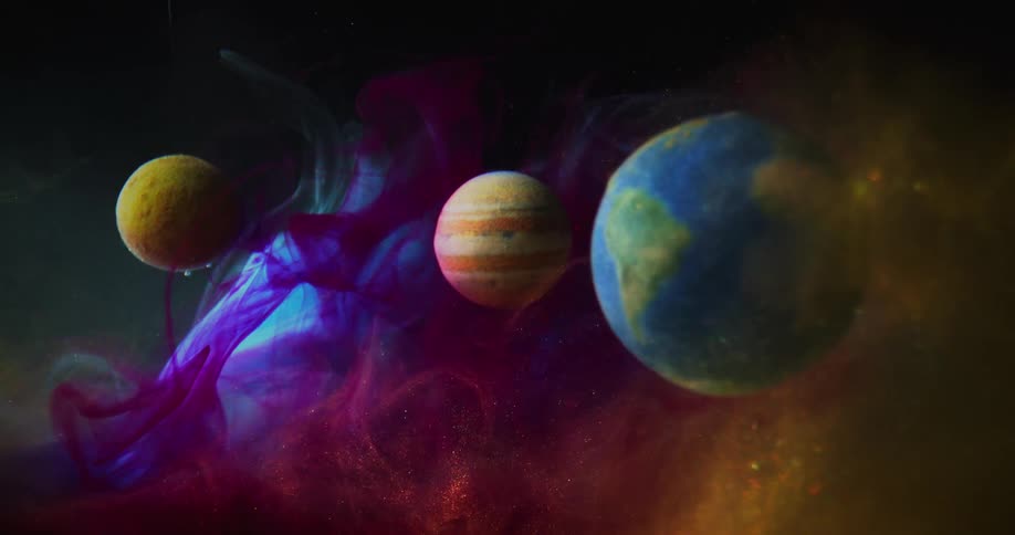 Swirls of colorful paint and dye glitter and swirl around a model of the solar system