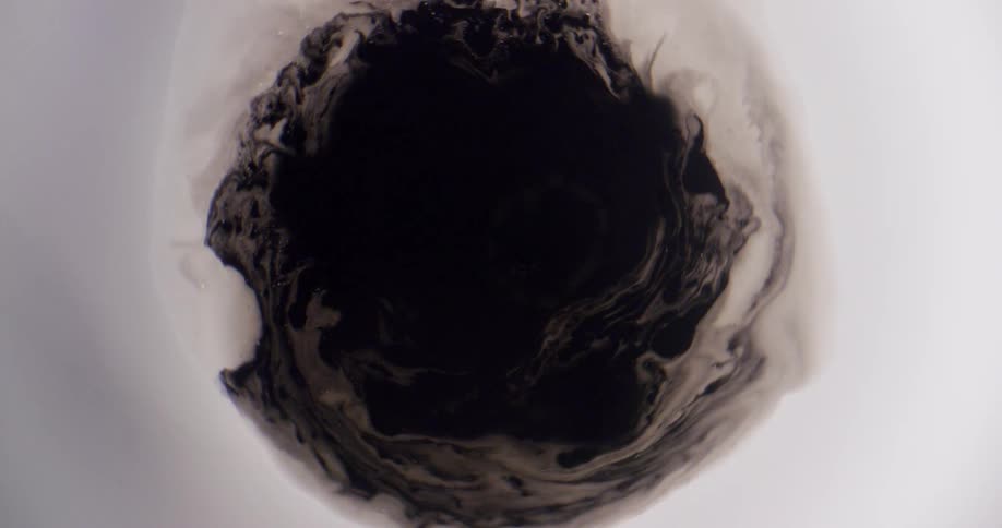 A black mass rotates in a white substance and they blend together as it turns
