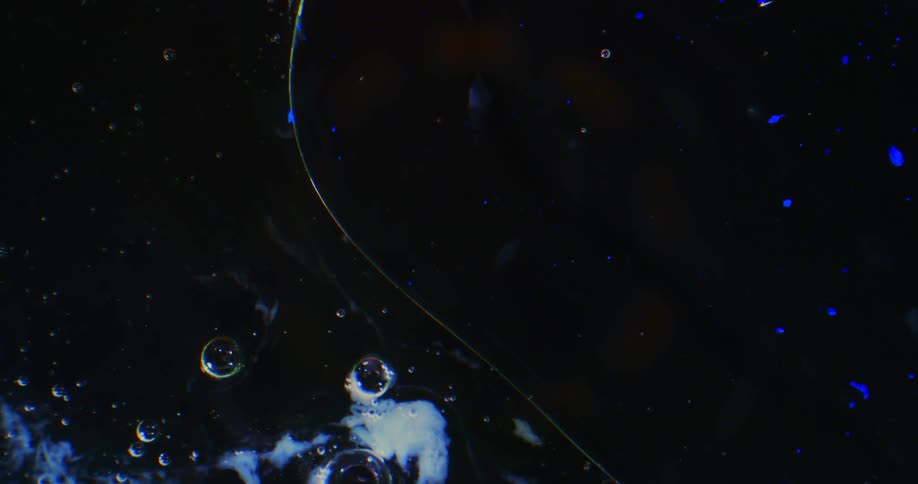 Bubbles floating in liquid with blue spots of light and milky clouds against black