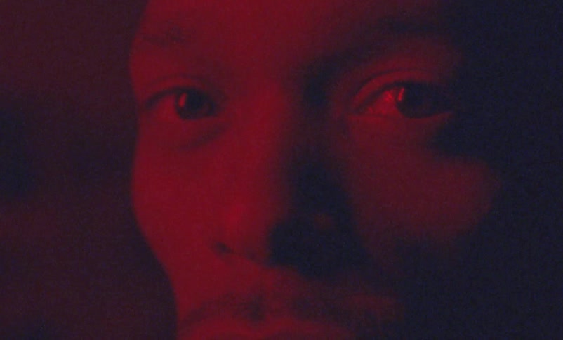 A man under red light is looking to his side