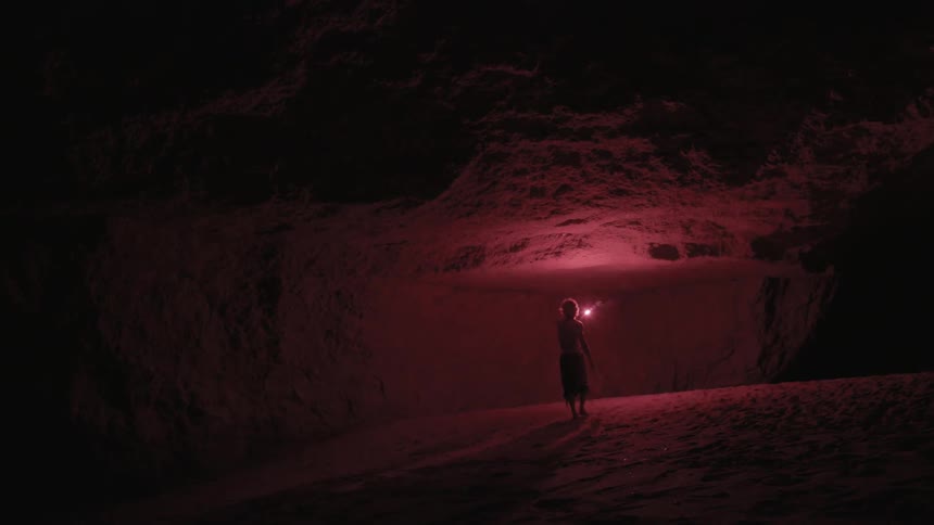 A man holds a flare as he walks in a cave