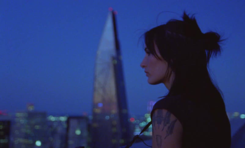 A woman with a camera around her neck looks out at the city skyline
