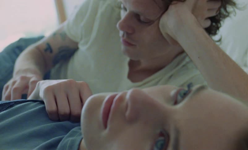 Man strokes womans arm as they lie on bed