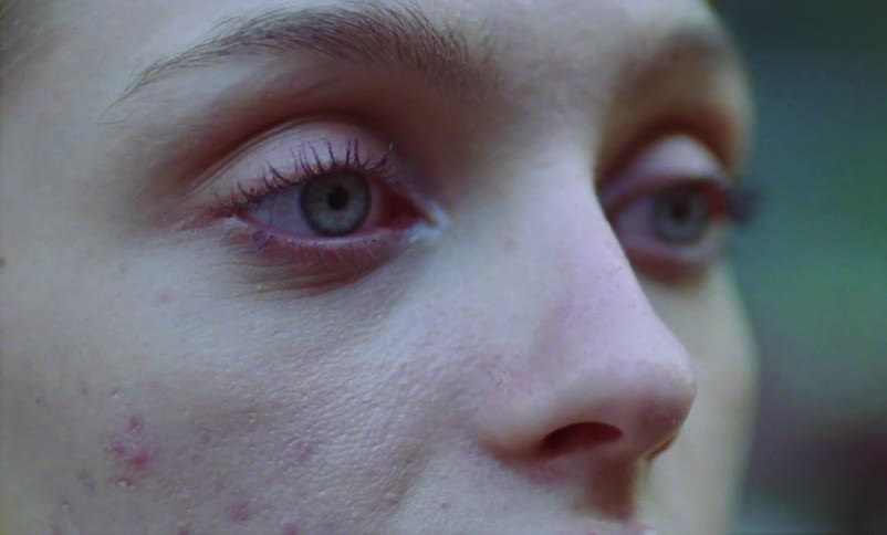 A woman is looking to the side and then turns her eyes to the camera
