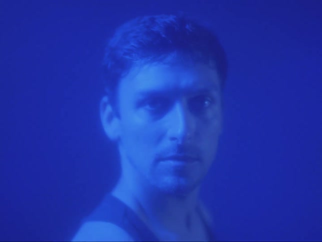 A man staring straight ahead as he turns his shoulders and changes his expression