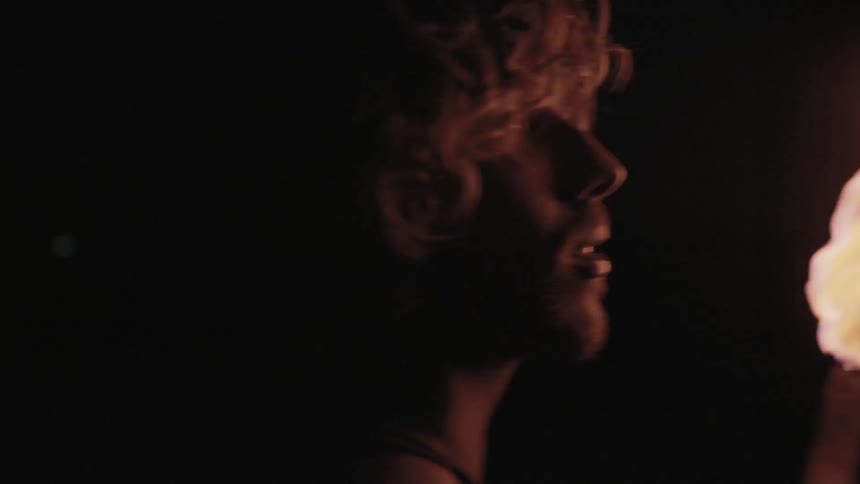 A man searches around a dark area with a torch
