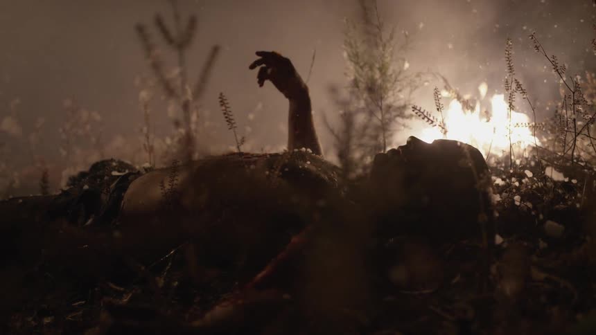 A man lies on the ground near a fire