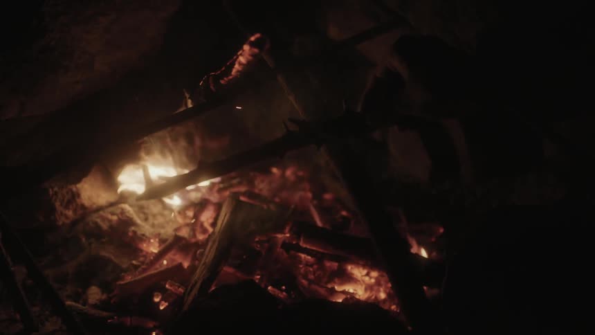 A man poking a stick into a campfire