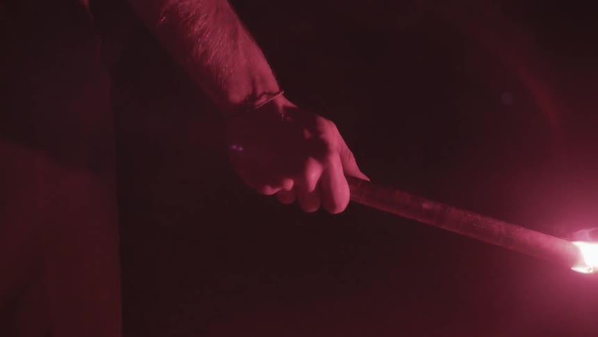 A person is holding a flare in a dark area