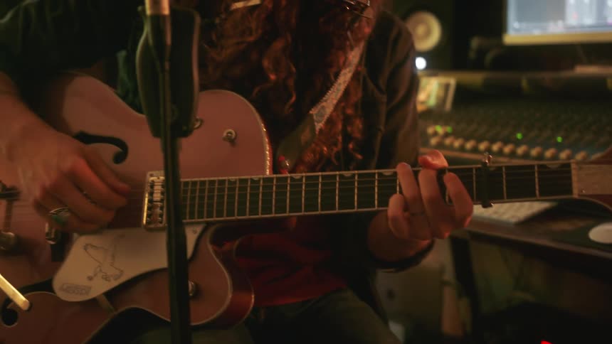 A man adjusts his guitar and strums it