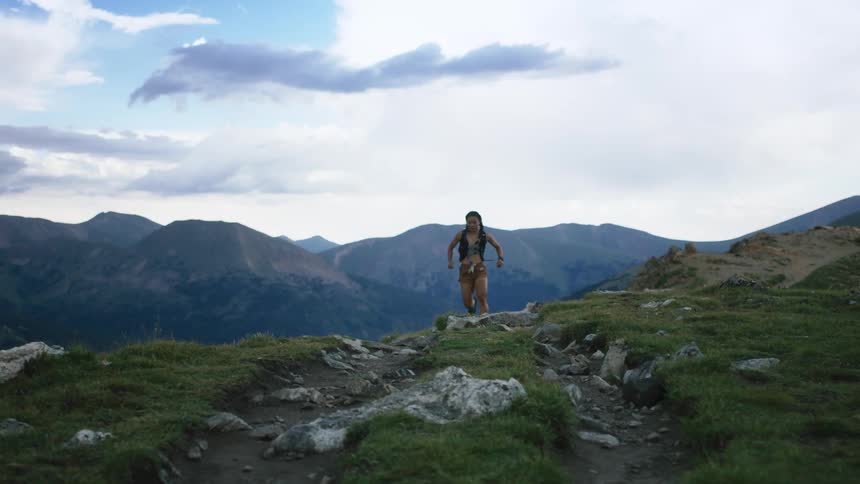 A woman jogs up and down a rocky hill