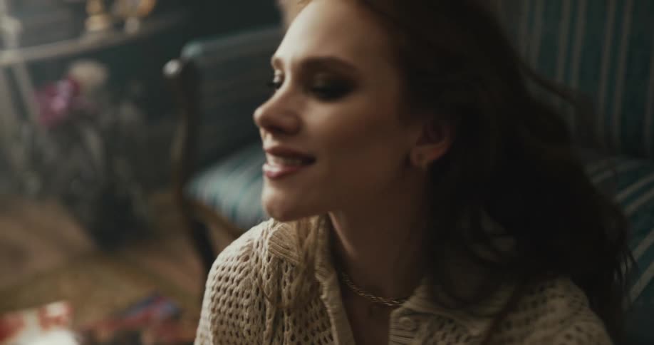 A woman smiling and dancing while sitting on a living room floor