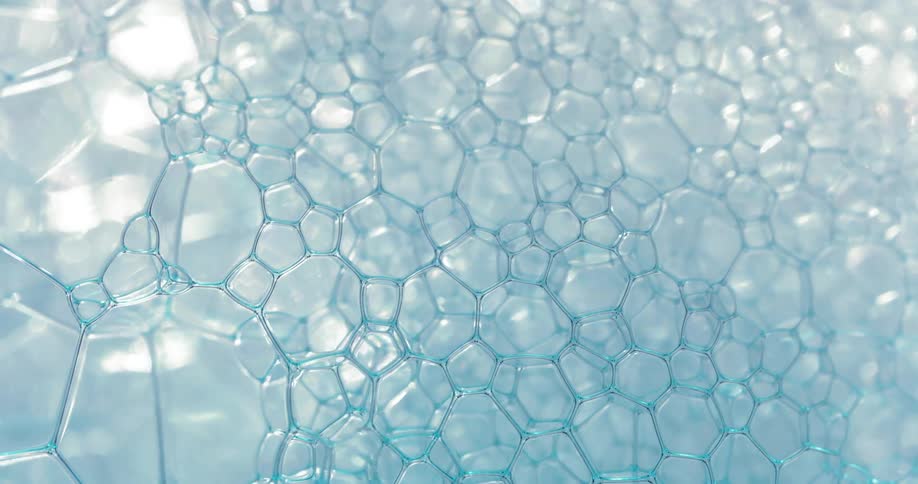 Bubbles and cells form and pop on the surface of water with light reflecting