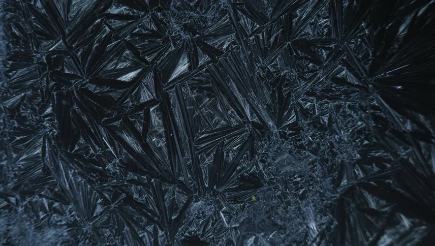 Light shines on black pieces of shard melded together as a small light moves over the surface