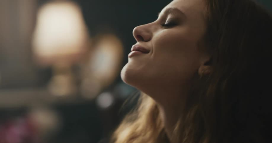 A teenage girl singing and dancing while sitting on the floor at home