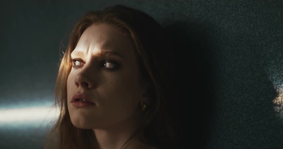 Womans eyelashes can be seen in shadow cast by her head onto wall