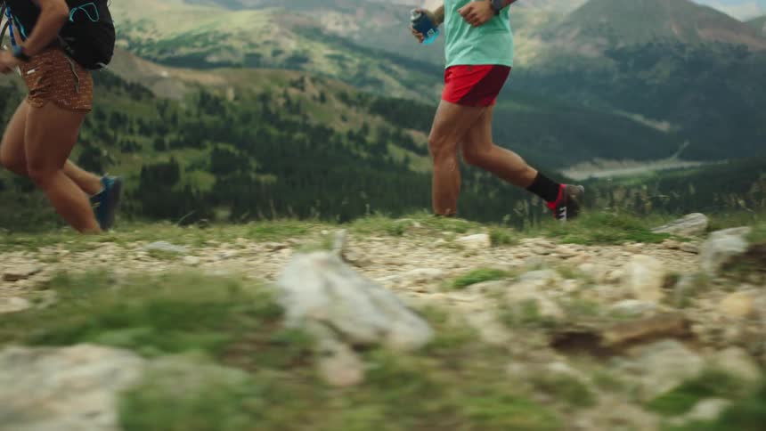 Three people jog down a trail in a canyon