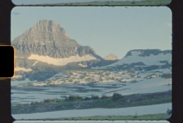 The peaks and slopes of a mountain range in glacier national park shot on 8mm film