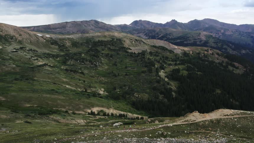 Aerial view of men jogging on track in green mountains