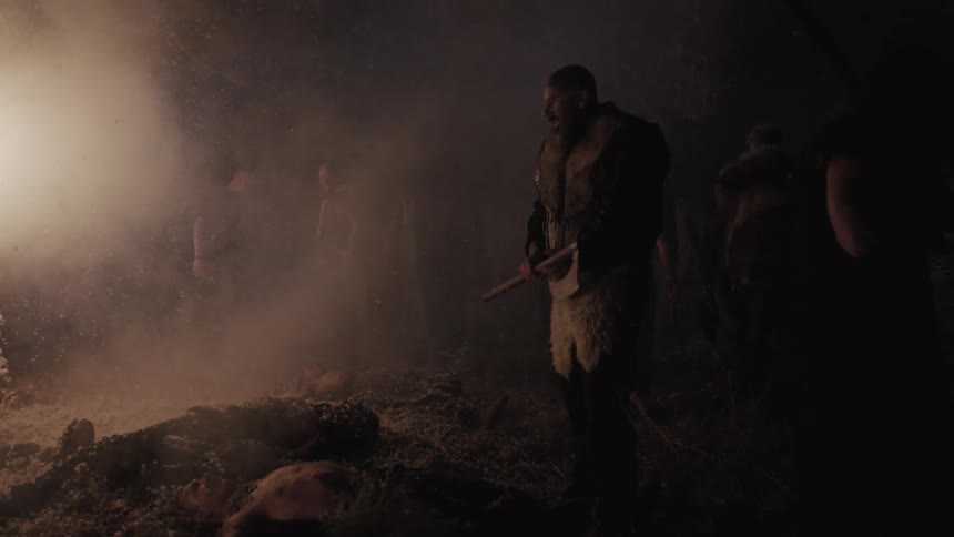 A group of men stand near a body shouting and raising their weapons in the air then they walk away