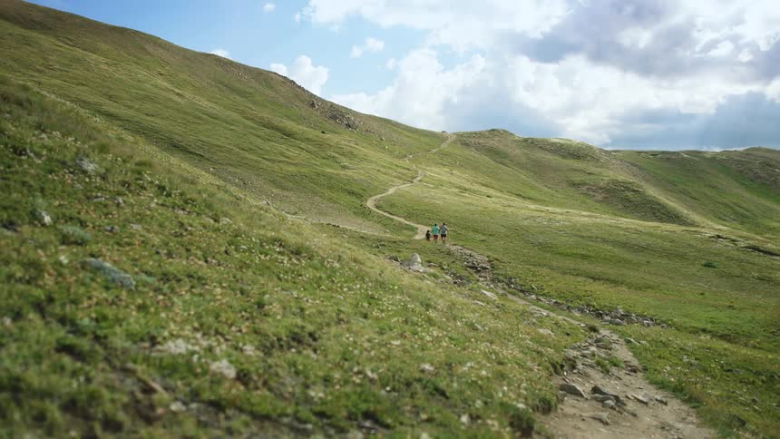 Three people on a dirt path on a rural hillside