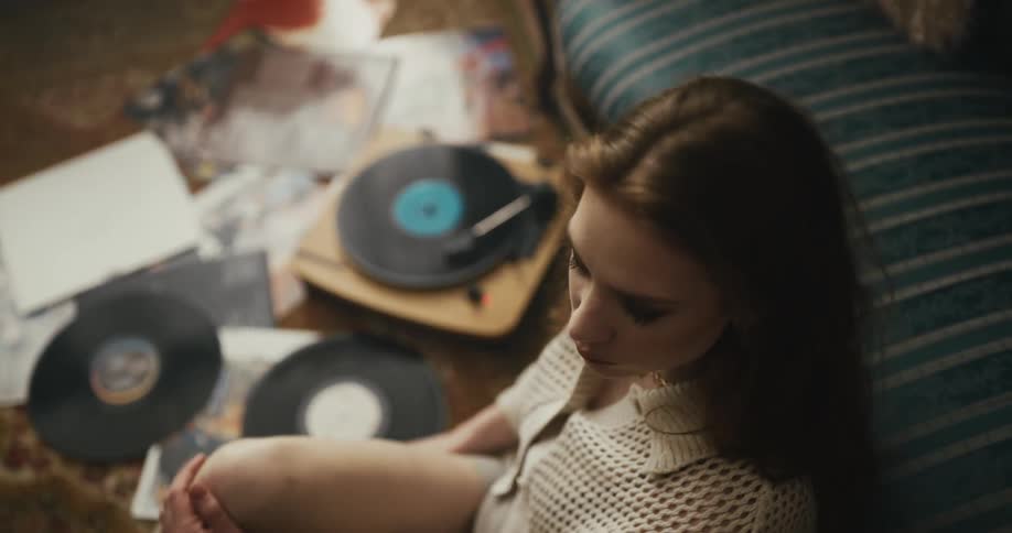 Close up of a young woman sitting on the living room floor dancing and singing to music played on vinyl