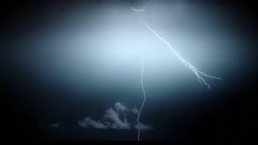 Slow motion footage of a lightning strike from an intense electric storm over a field at night