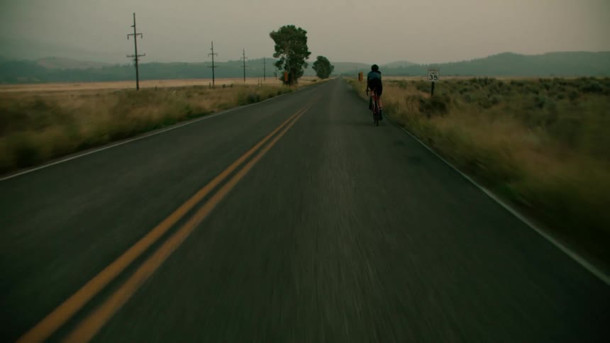 A woman riding a bicycle on a paved rural road