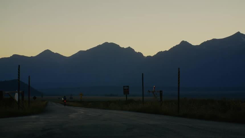 A bicyclist riding on a rural road at dusk