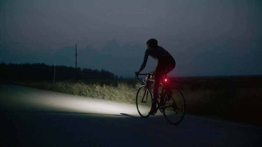 A woman riding a bicycle on a rural road at dusk